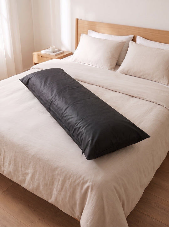 Black protective case for dakimakura lying on a bed, zipped closed
